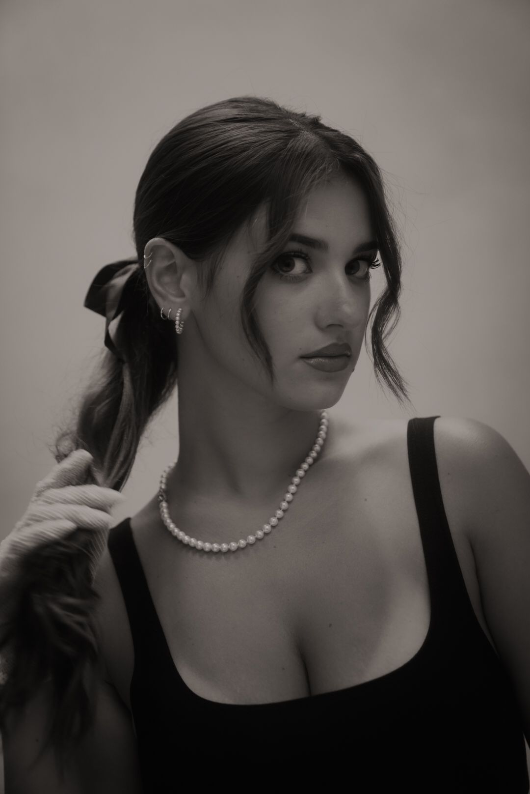 Vintage-inspired black and white portrait with pearls and tied-back hair.