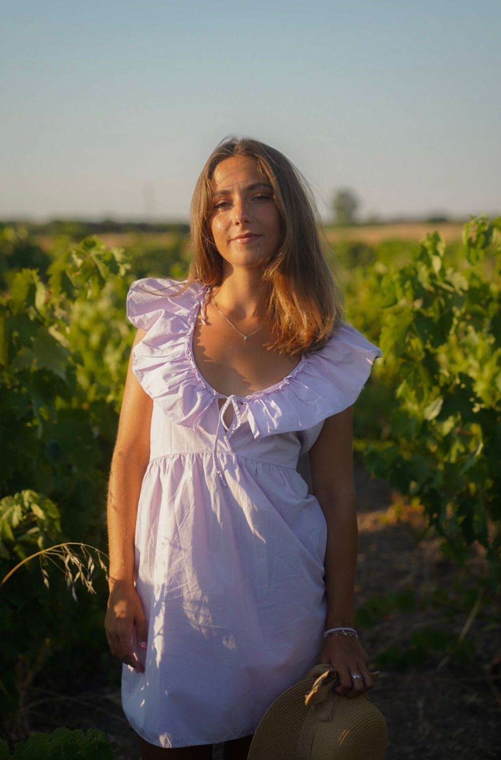 White ruffle dress worn in a sun-drenched vineyard setting during golden hour.