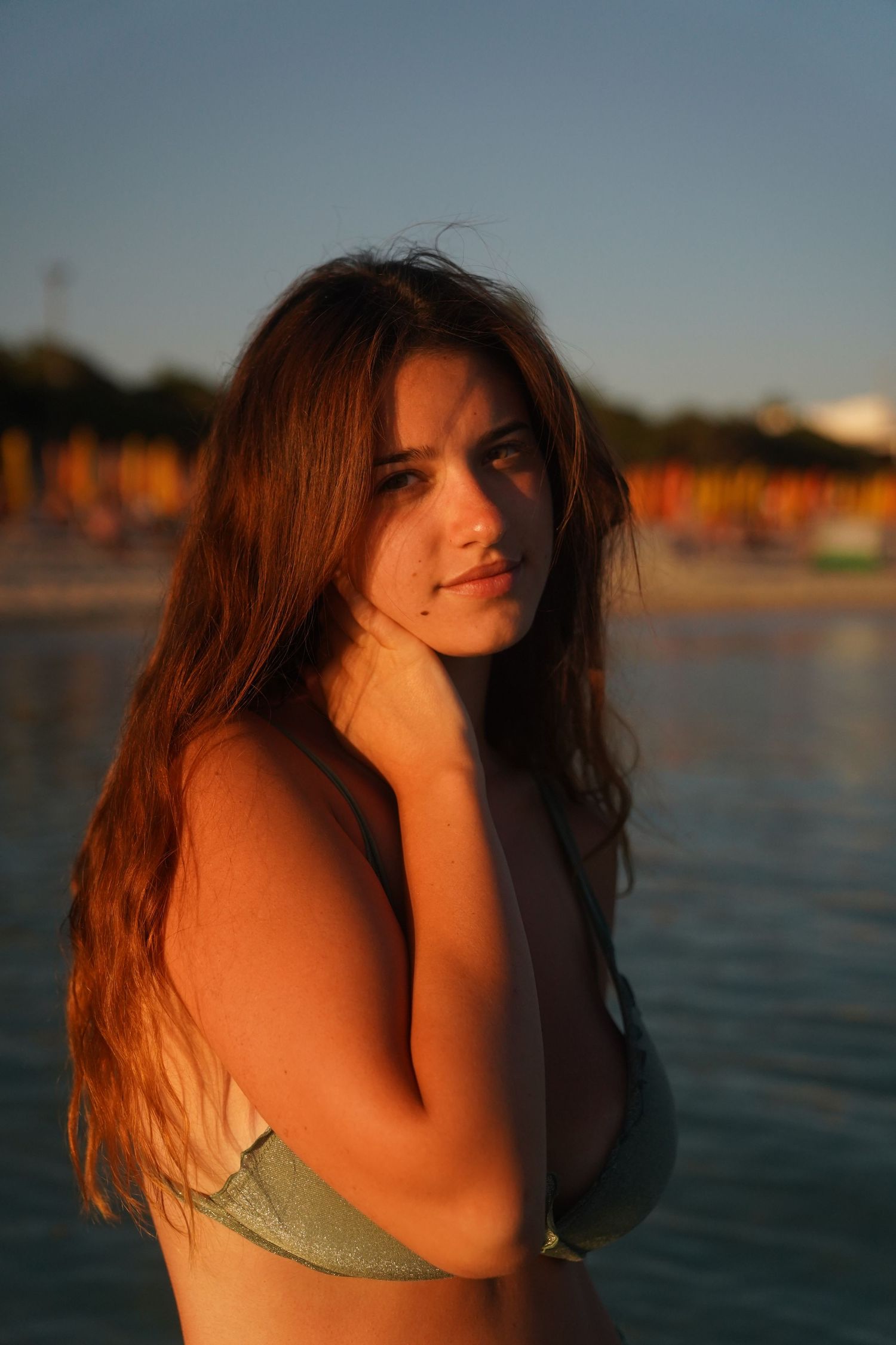 Sunset portrait at beach with warm golden lighting and ocean background.