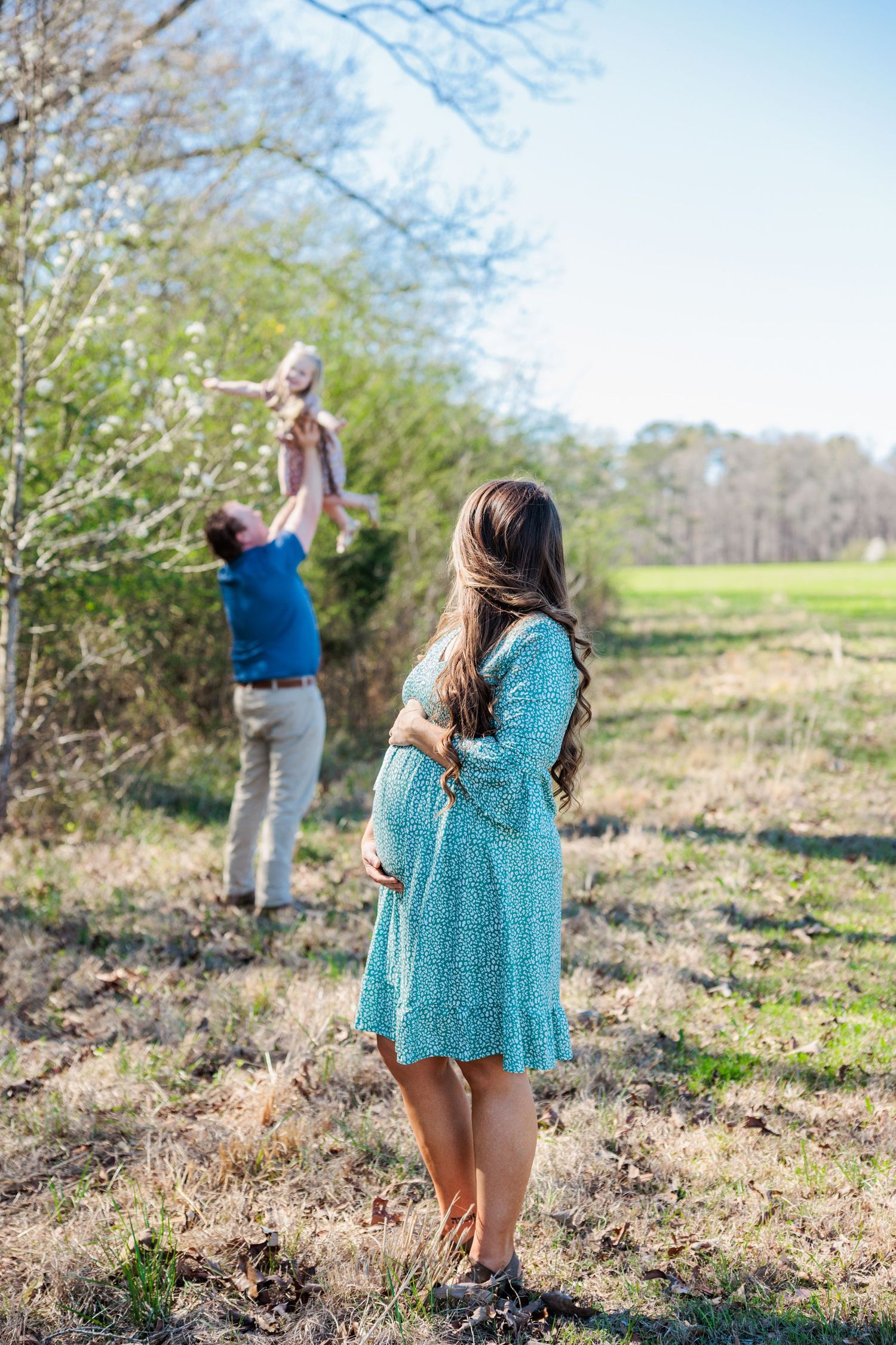 Family enjoying a sunny day outdoors as they play together in a scenic field.