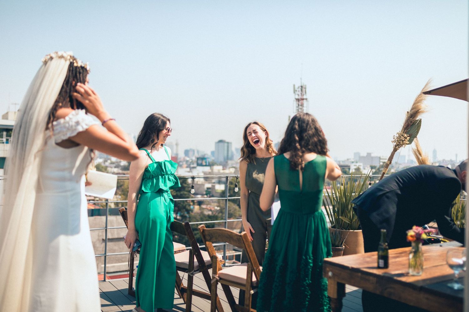 Wedding party gathering on rooftop terrace with city skyline view.