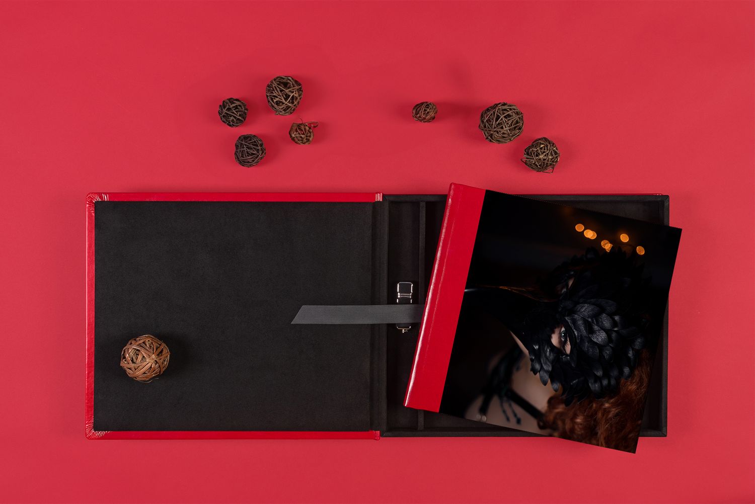 Red photo album with decorative pine cones displayed on a dark surface.
