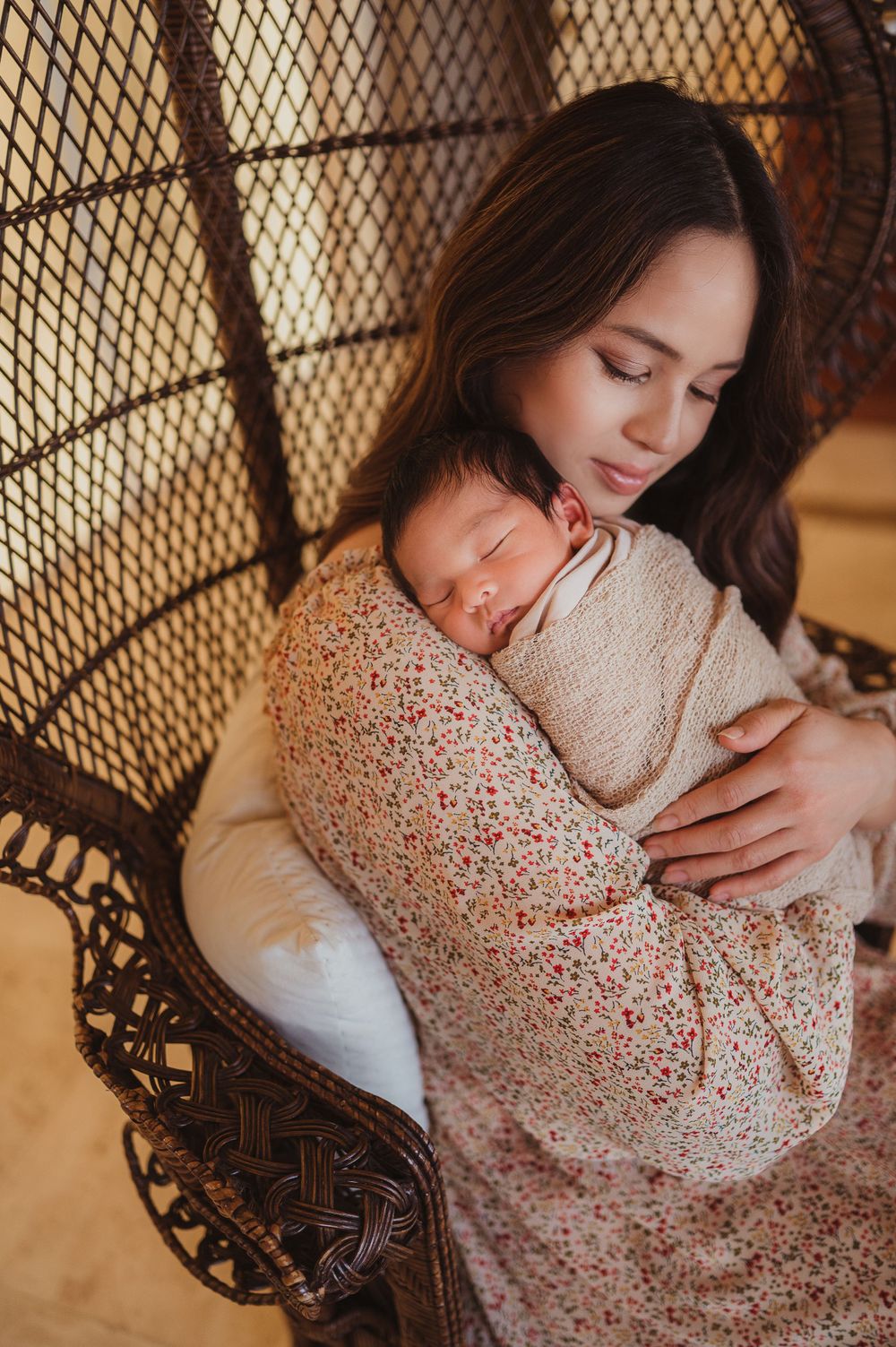 Mom holding her newborn baby sitting in a chair in their house.