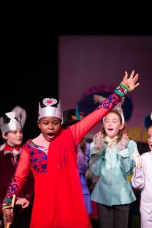 Performers in bright costumes express joy during an energetic stage performance.