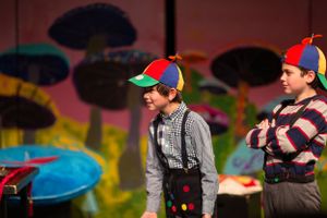 Two performers in casual costumes act against a colorful fantasy backdrop.
