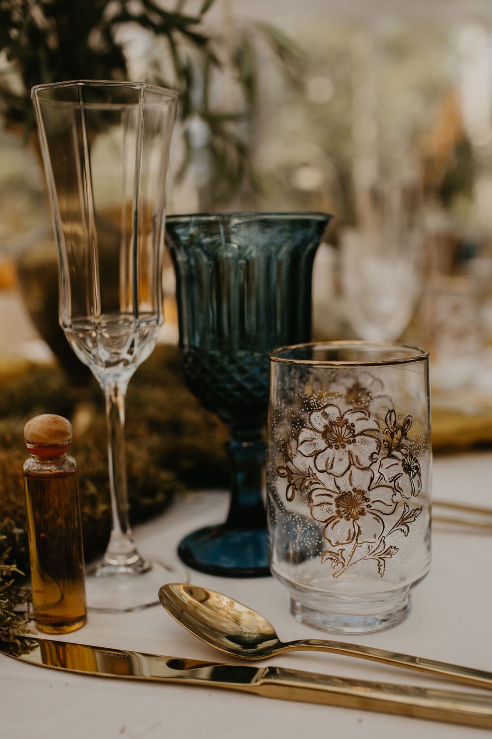 Elegant glassware set featuring champagne flutes, blue goblets, and floral etched glasses.