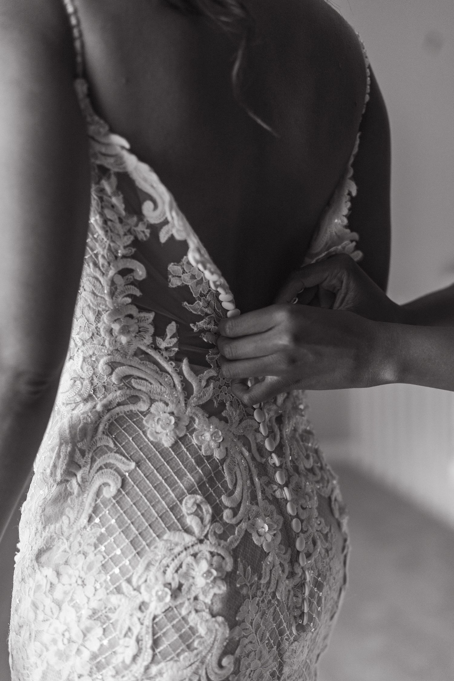 Artistic black and white photo showing intricate lace pattern detail on wedding dress.