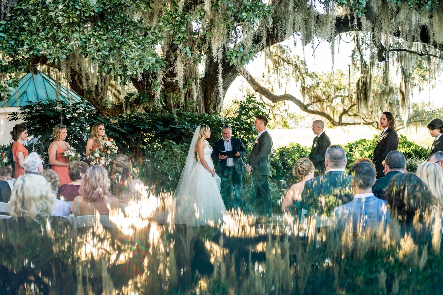 Outdoor wedding ceremony setup under Spanish moss draped oak trees.