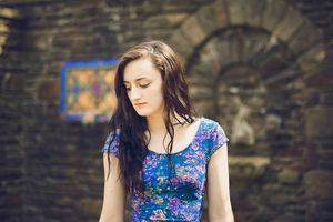 Portrait sequence featuring a floral dress against rustic brick wall backdrop.
