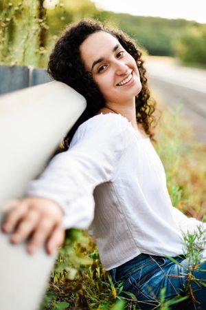 Outdoor portrait series in white top and jeans showing playful poses in natural lighting.