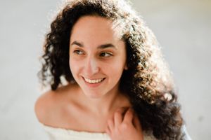 Studio portrait series featuring natural curly hair and bright expressions against light background.
