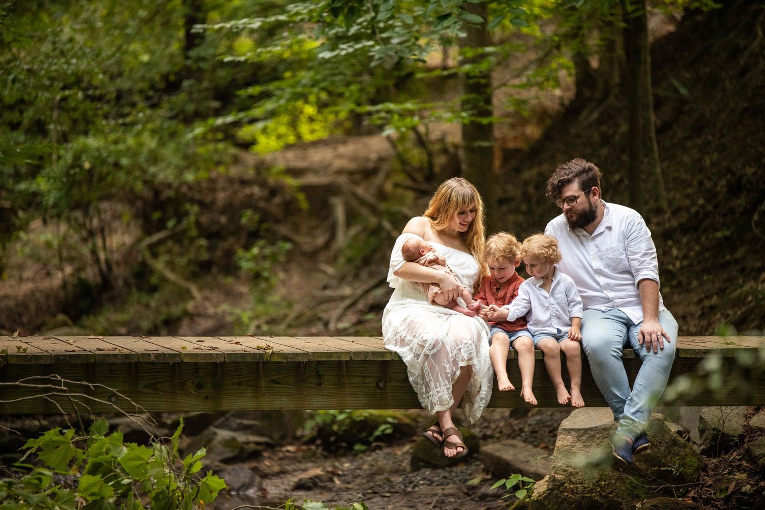 Family spending quality time together on stone steps by a peaceful woodland pond.