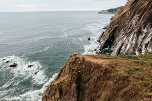 Dramatic coastal cliffs meet the ocean with crashing waves and rugged terrain.