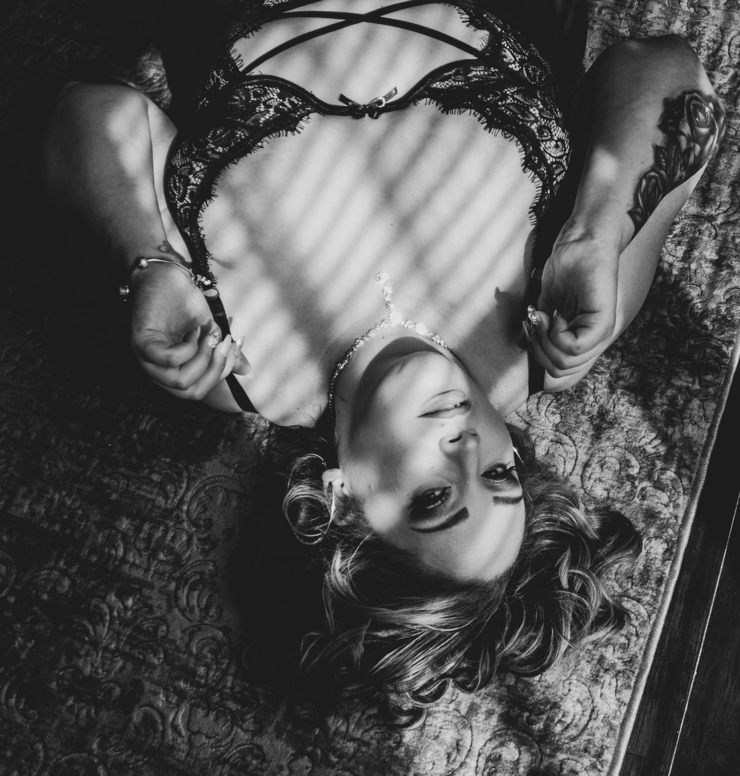 Black and white artistic portrait with dramatic shadows through venetian blinds.