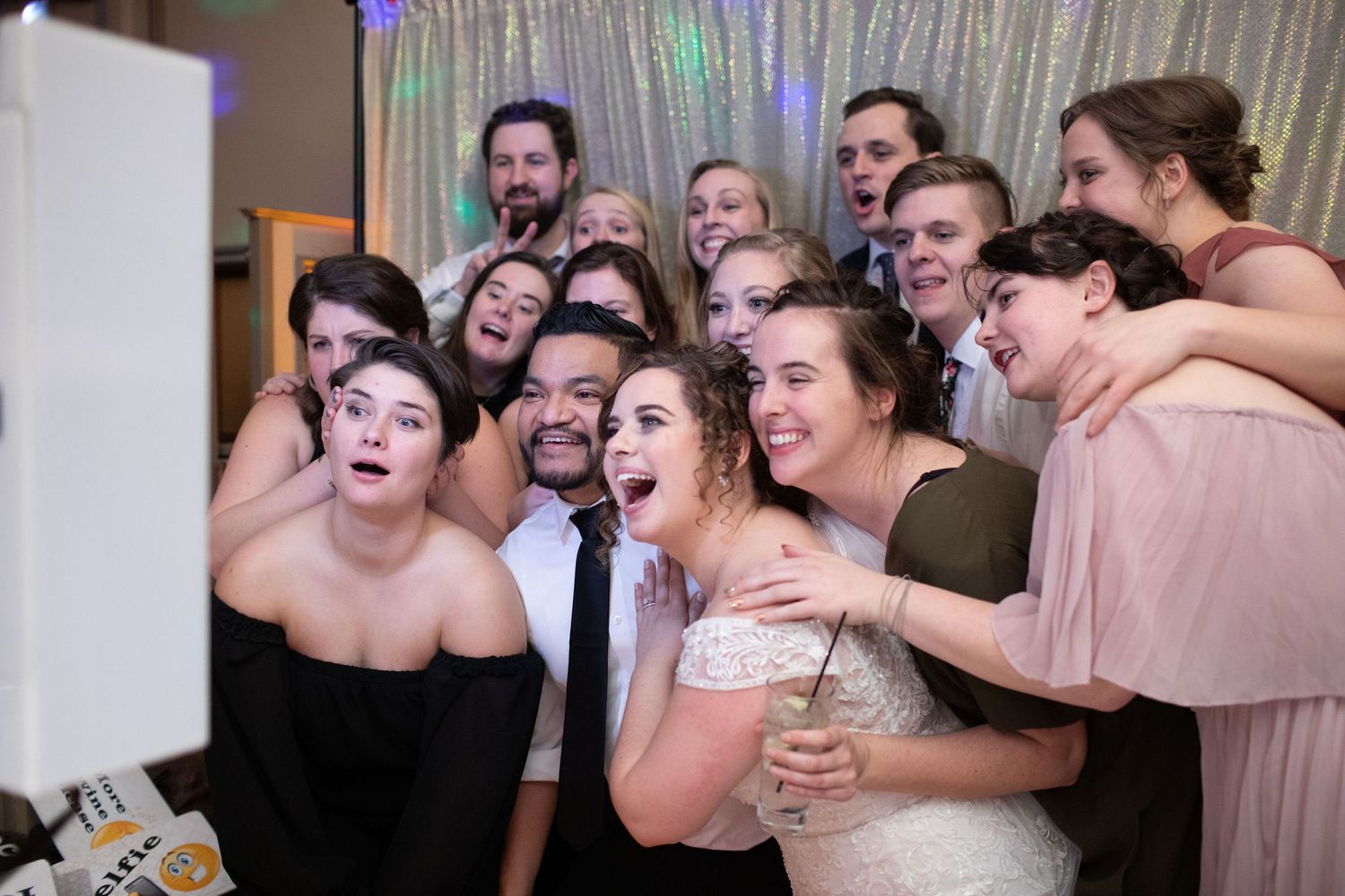 Wedding party members crowded together laughing and having fun during a photo session.