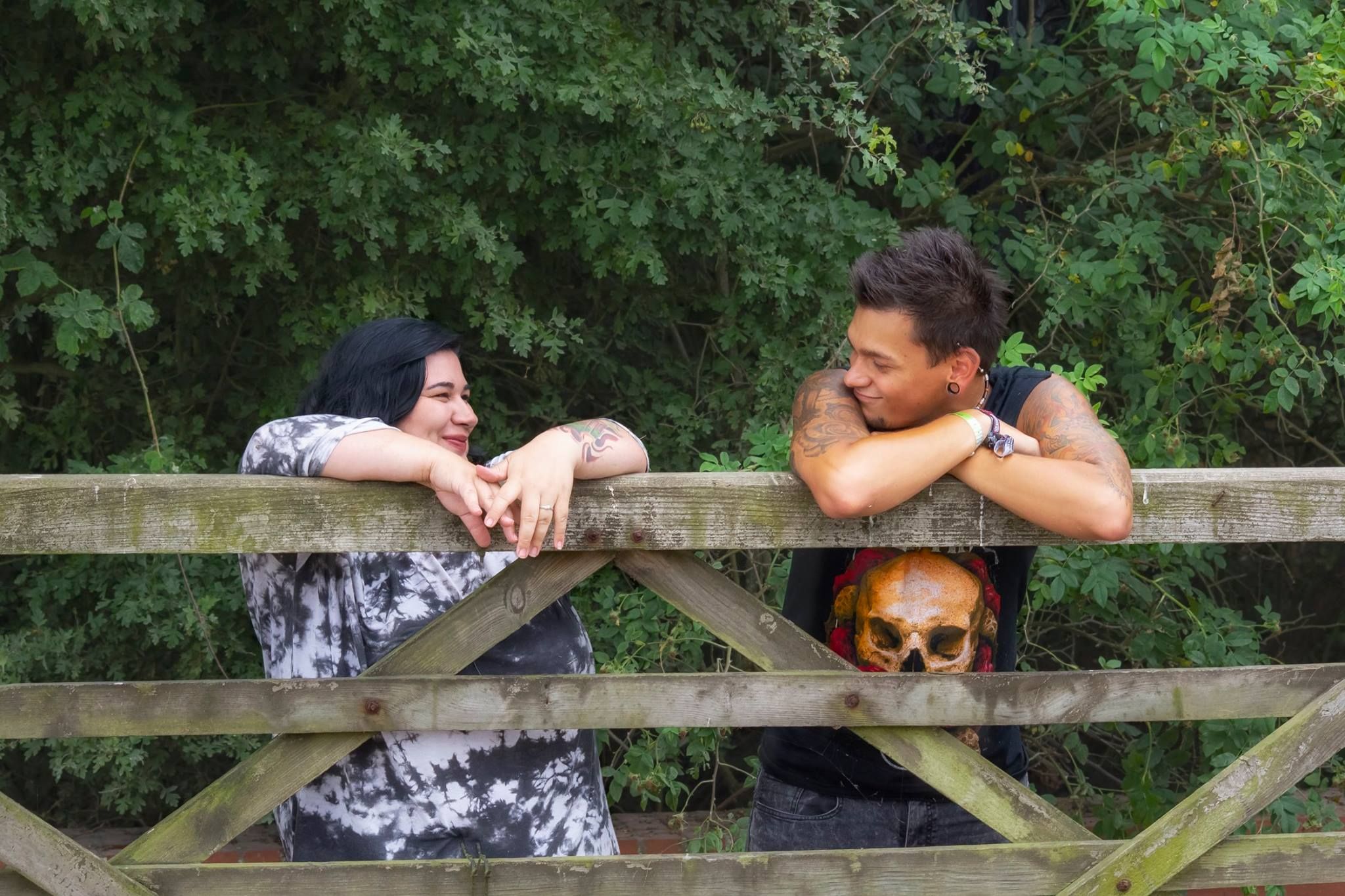 A playful couple leaning on a wooden fence sharing a laugh together.