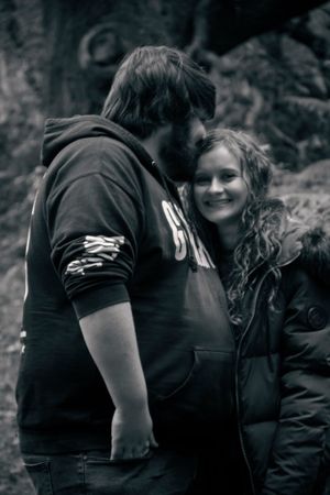 A black and white intimate portrait of a couple in winter clothing sharing a close moment.