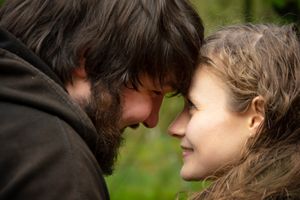 An intimate close-up portrait of a couple sharing a tender moment outdoors in soft natural light.