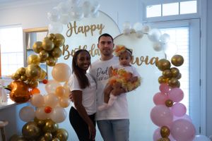 Birthday celebration with balloon arch decorations in gold, white and pink tones.