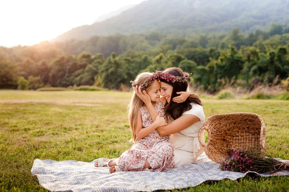 A tender moment shared on a picnic blanket with mountains and sunset in the background.