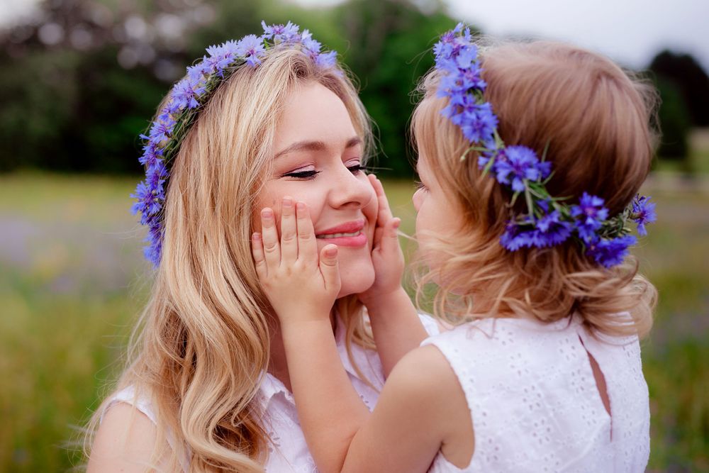 A touching moment between two people wearing matching floral crowns in a sunlit meadow.