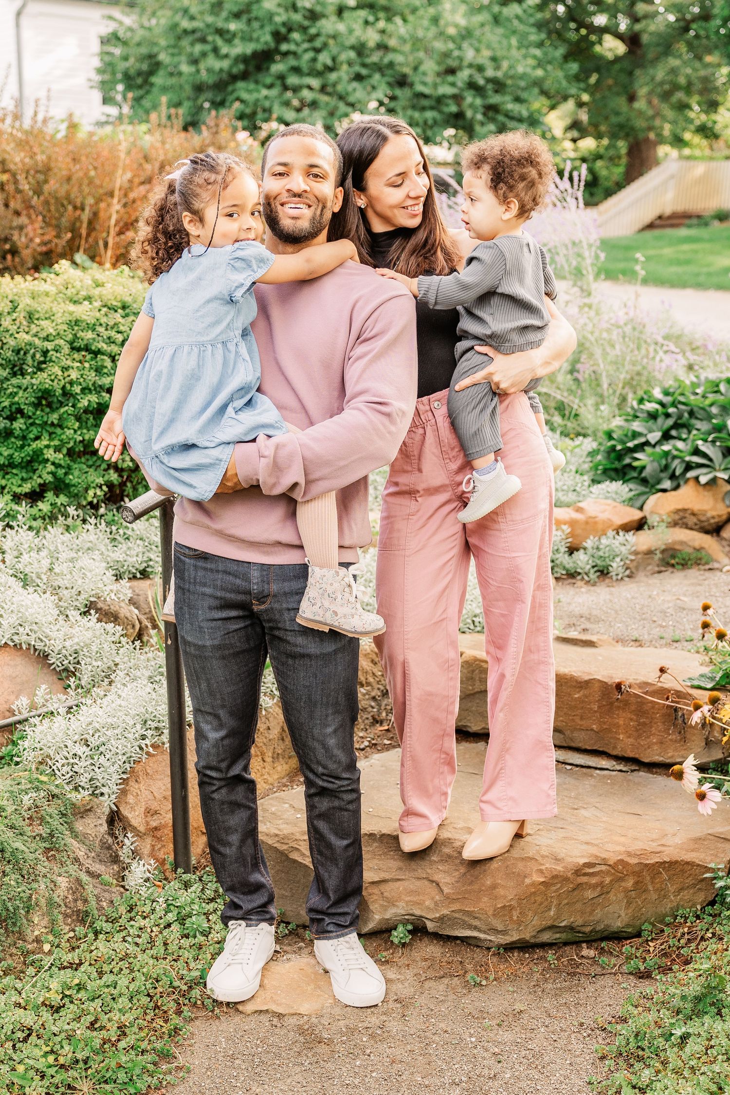 Family shares playful moments together while standing on stone steps in a garden.