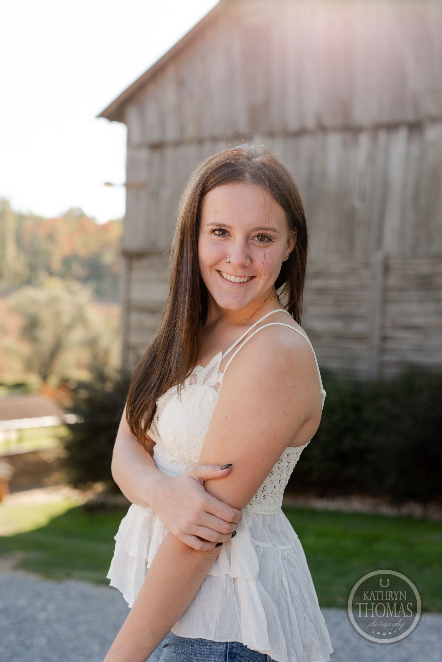 Casual portrait in white lace top against rustic barn backdrop.