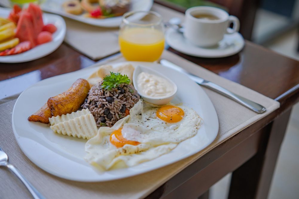 Gourmet breakfast spread with eggs, fruits and pastries served on white plates.