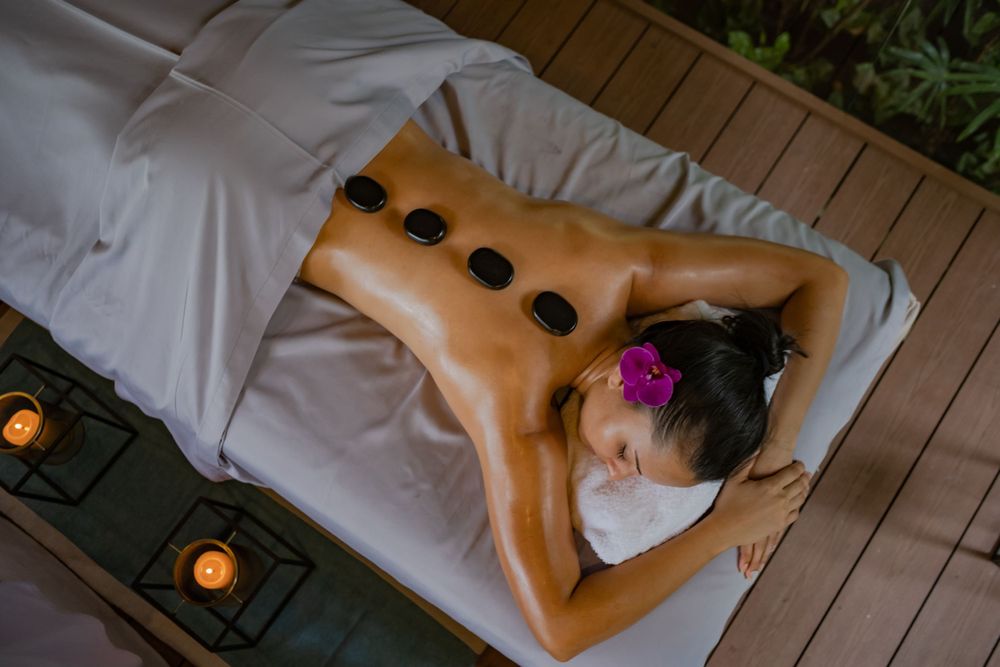 A relaxing hot stone massage treatment with black stones placed along the spine on a massage table.