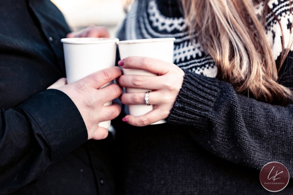 two hands holding hot chocolate showing off engagement ring