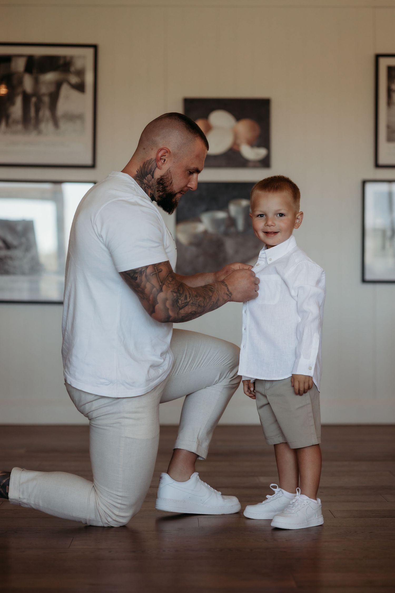 Sweet moment between parent and child in matching white outfits on hardwood floor.