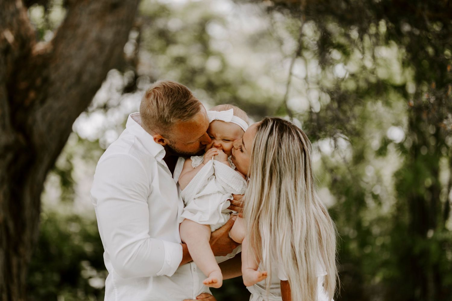 A tender family moment captured in a sunlit forest setting with soft bokeh effects.
