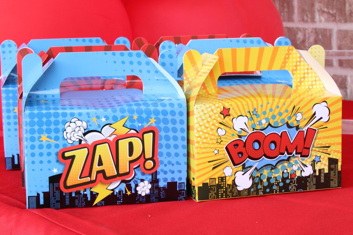 Colorful superhero themed party favor boxes with comic book style ZAP and BOOM designs.