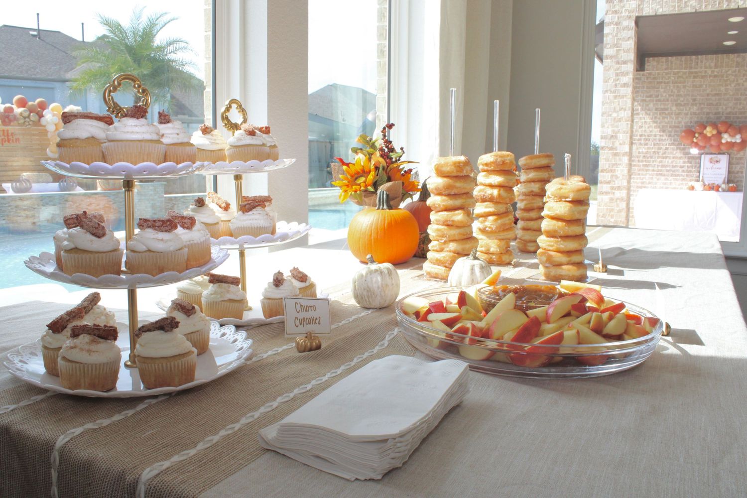 Elegant party dessert spread featuring cupcakes, donuts, and pastries displayed on tiered stands with orange accents.