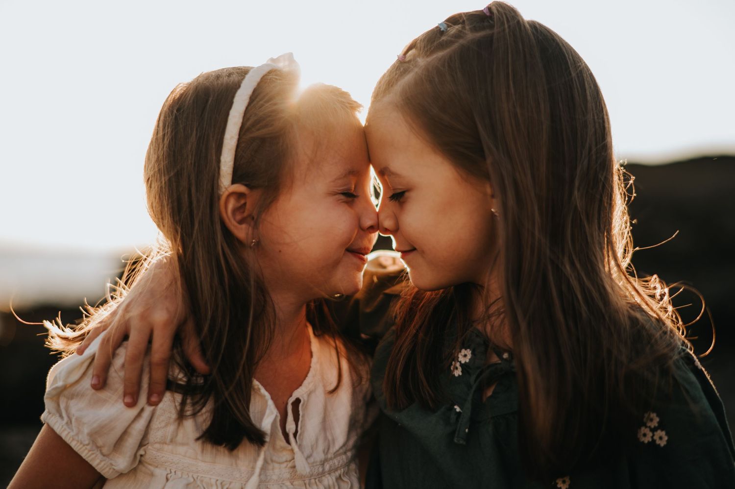 sisters snuggle together at Beavertail in Jamestown during a family session with Harlow & Stone Studios