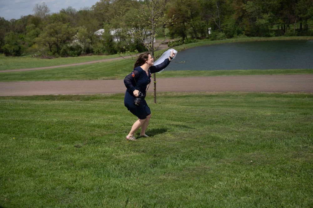 A dancer leaps gracefully across a green lawn with a lake in the background.
