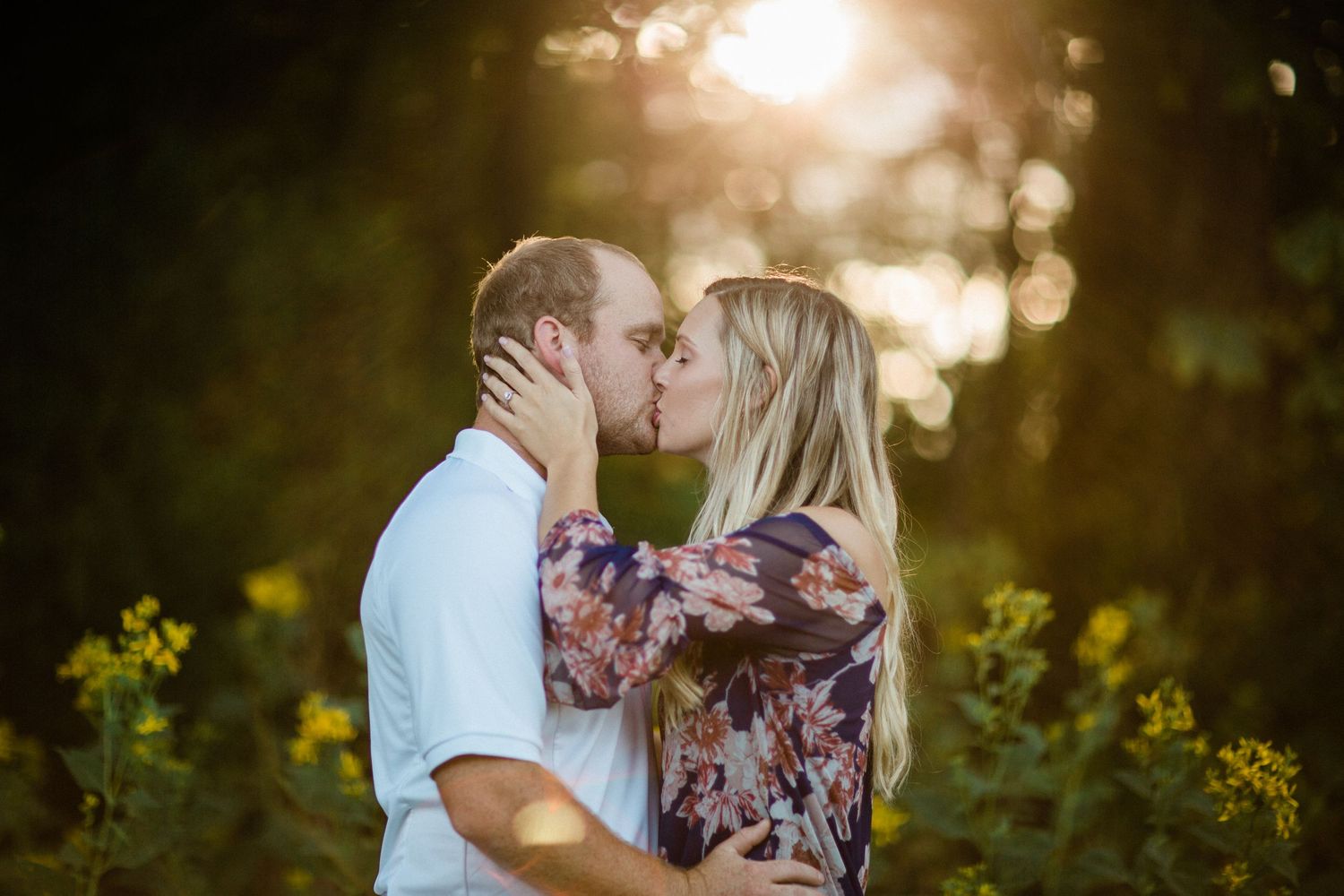 Couple sharing intimate kiss during golden hour outdoor photo session.