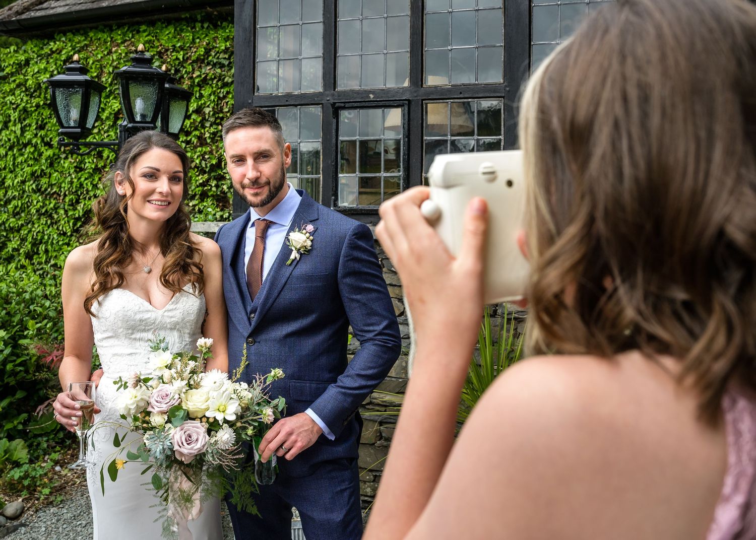 Guest taking picture of bride and groom outside Broadoaks Country House Hotel