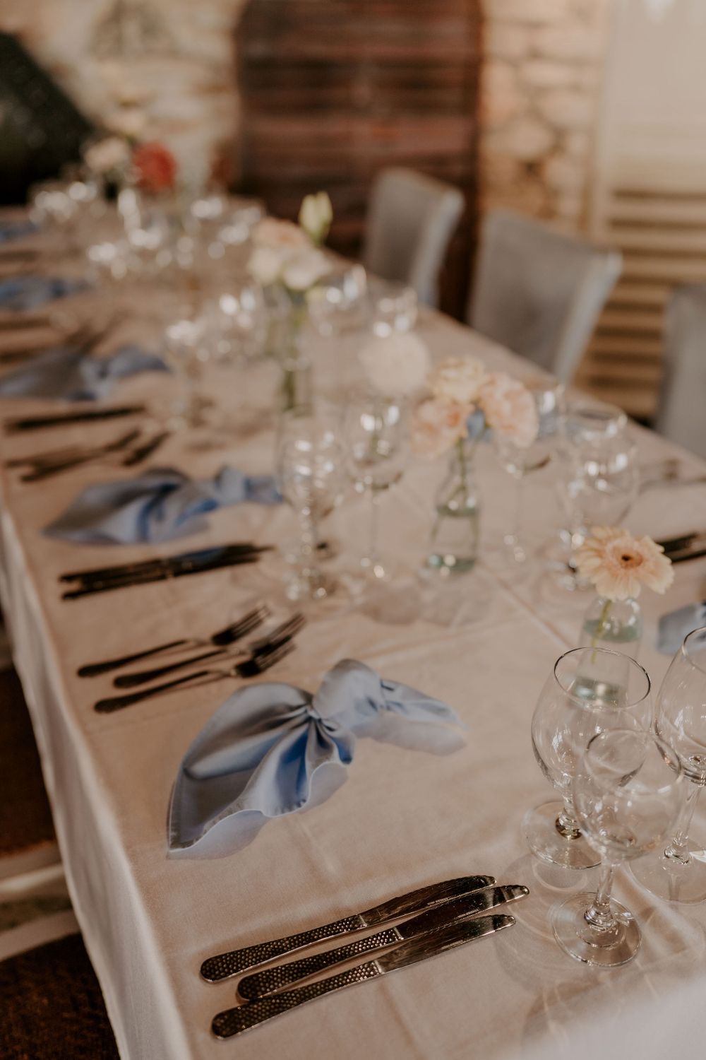 Elegant wedding reception table setting with blue napkins and crystal glassware.