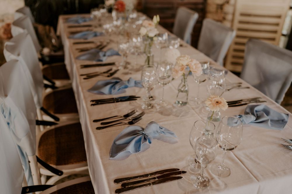 Wedding reception table decorated with place settings and crystal glasses.