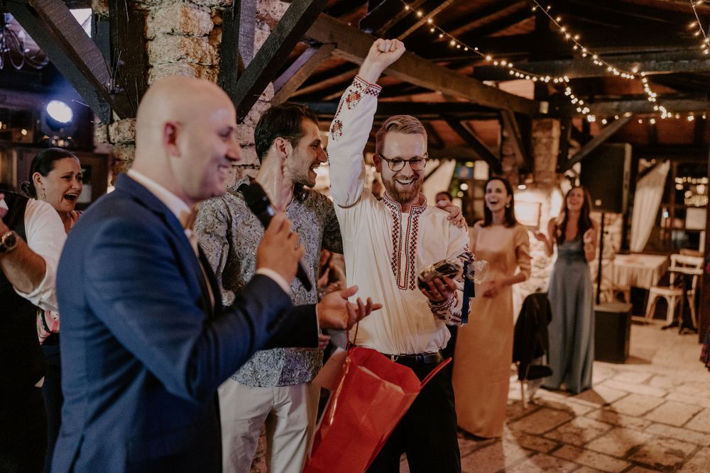 Party guests raising their hands in celebration during a festive indoor event.
