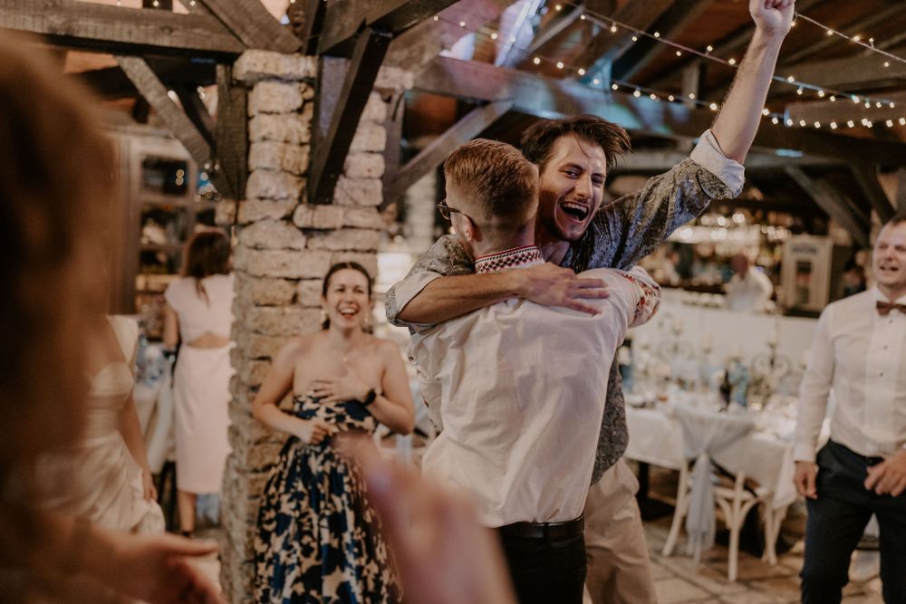 Guests dancing enthusiastically at a rustic venue decorated with string lights.