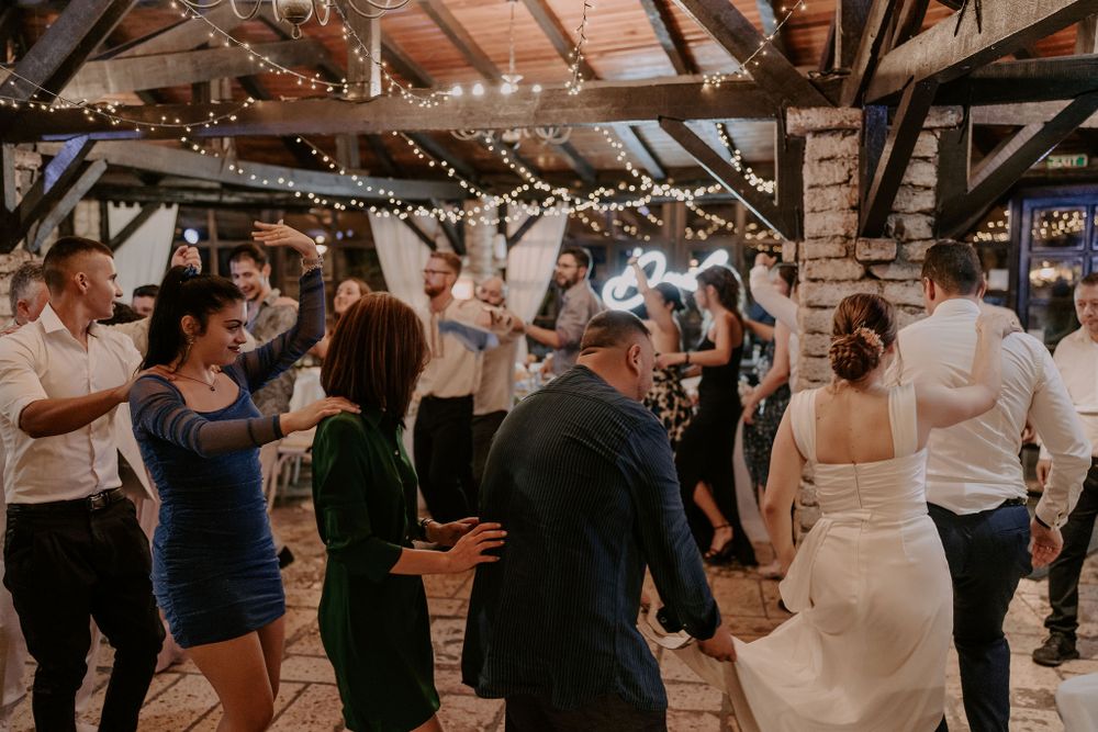 Lively dance floor scene at a wedding reception with string lights overhead.