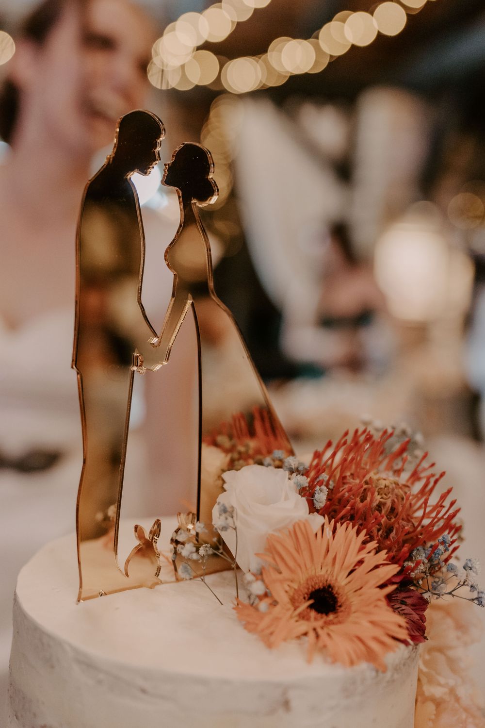 Modern wedding cake topper silhouette with romantic bokeh lighting and floral decorations.
