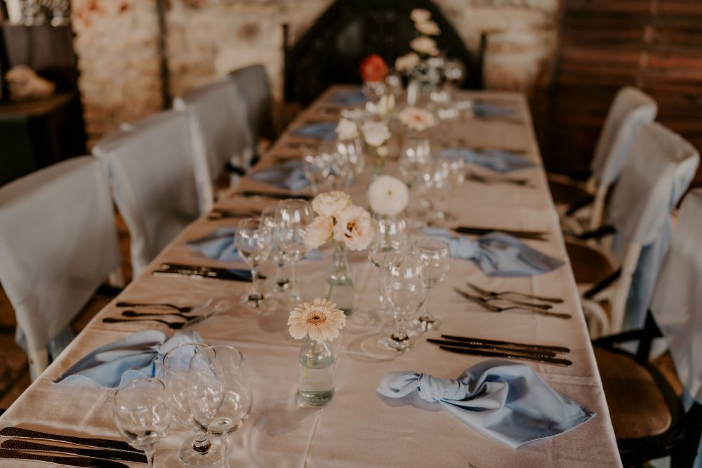 Elegant table setting with white linens, gray chairs, and crystal glassware for an upscale dining event.
