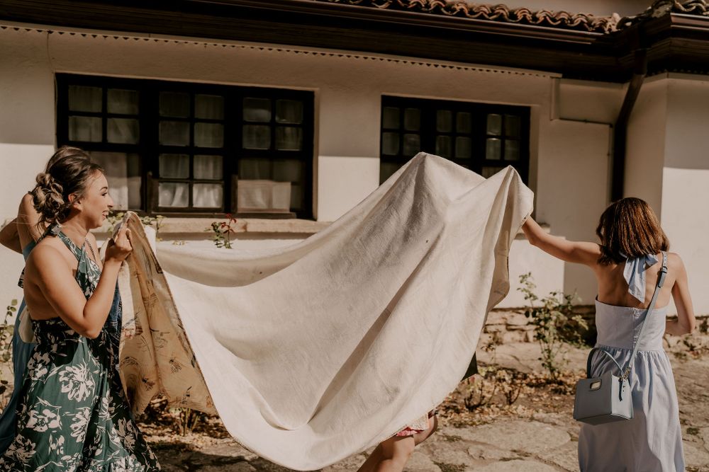 People holding a flowing white fabric outdoors against a building facade.