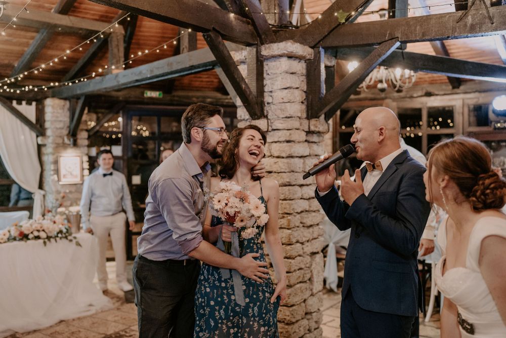 Wedding guests share emotional embraces during a reception in a rustic indoor venue.