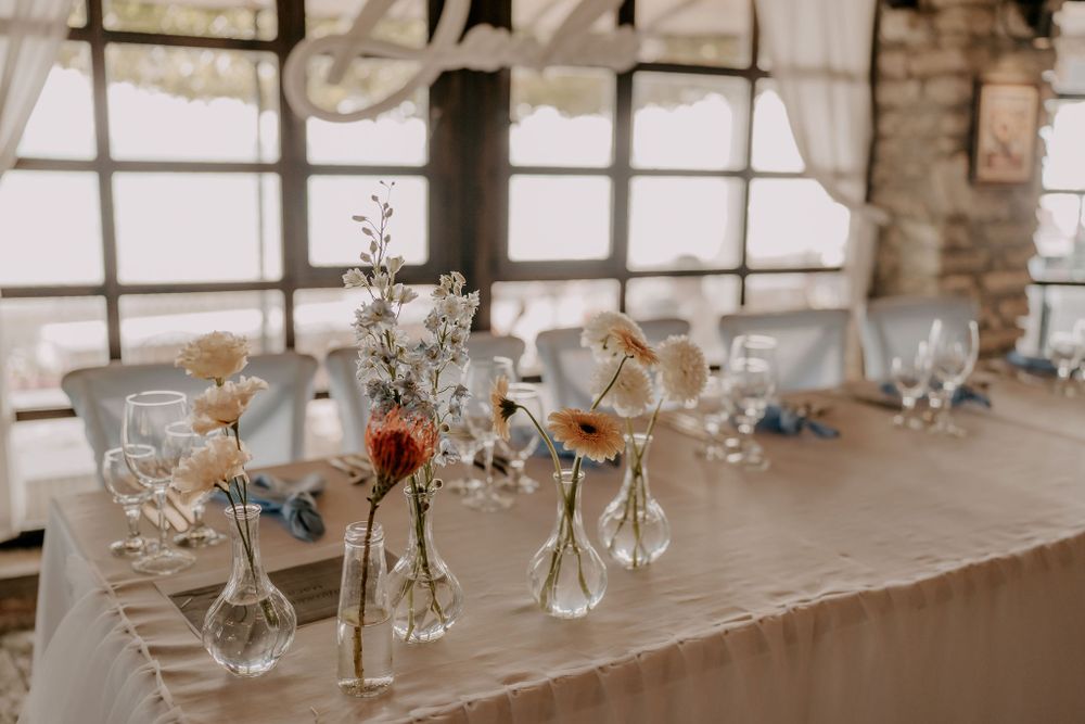 Delicate floral centerpieces with crystal vases arranged on white tablecloth.