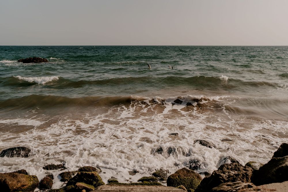 Dramatic ocean waves crashing against rocky coastline during sunset.