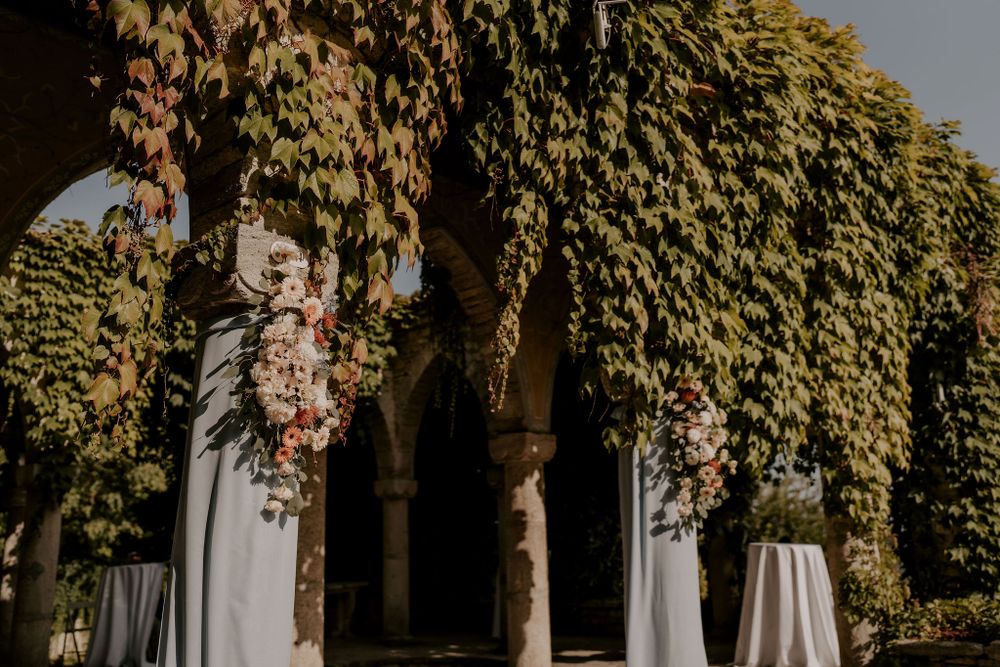 Elegant outdoor wedding venue with white chairs and blue fabric draping beneath autumn foliage.